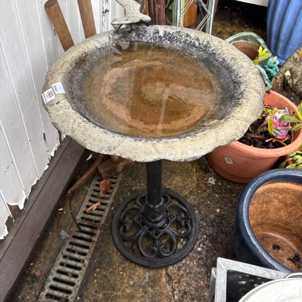 Vintage cast iron bird bath in a garden setting.