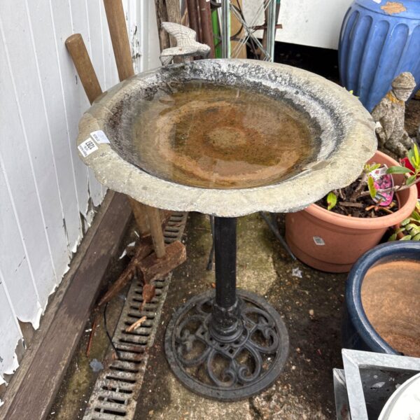 Vintage cast iron bird bath in a garden setting.