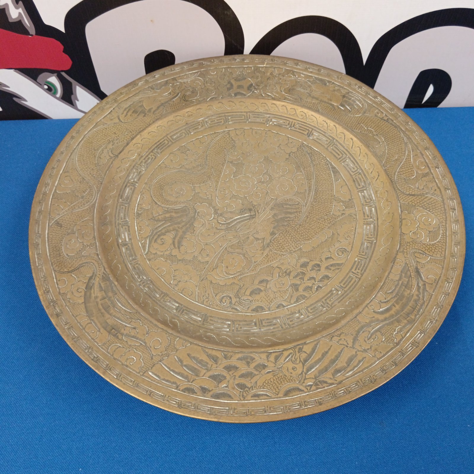 Antique Chinese brass plate with dragon design, detailed relief work.