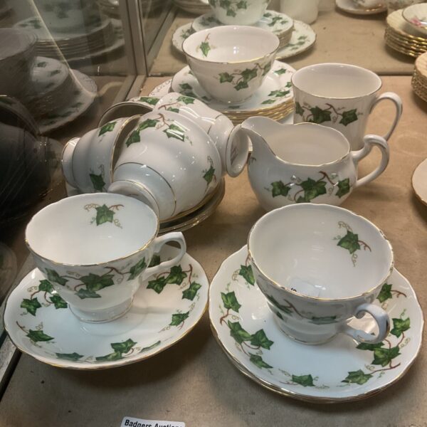 Vintage Colclough bone china teaset with ivy pattern displayed in a cabinet.