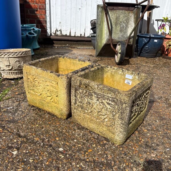 Pair of weathered concrete garden planters with floral design.