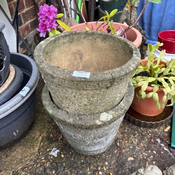 Pair of weathered concrete planters in a garden setting.