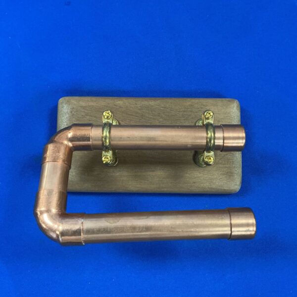 Rustic copper pipe loo roll holder on wooden base.
