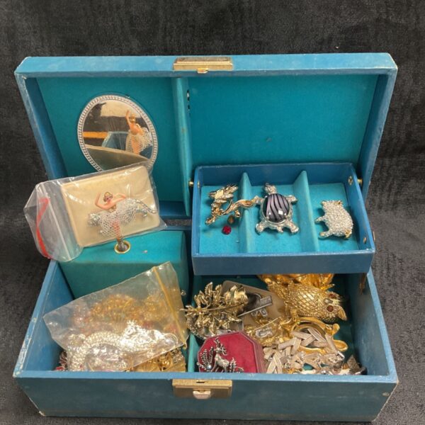 Vintage costume jewellery box filled with brooches and earrings.