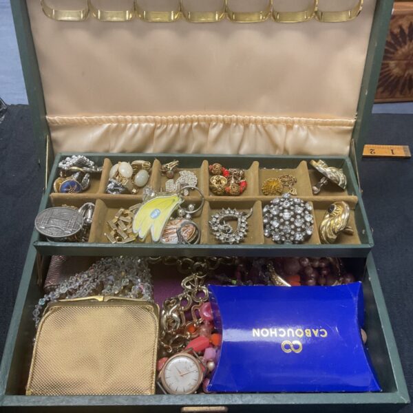 Vintage costume jewellery box filled with brooches and necklaces.