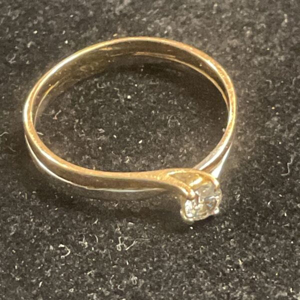 Close-up of a white and rose gold diamond solitaire ring.