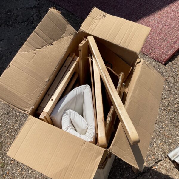Disassembled wooden baby crib parts in a cardboard box.