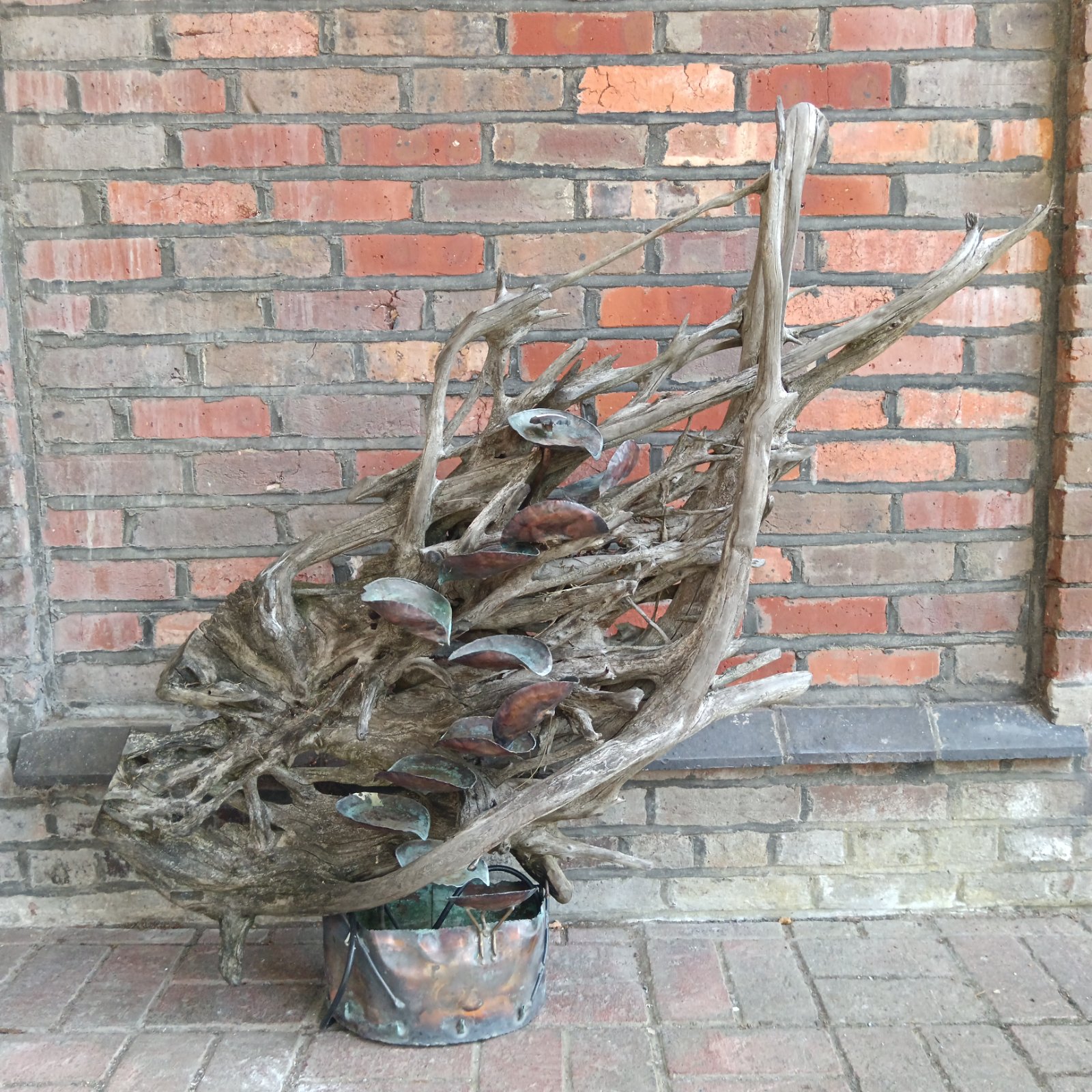 Unique driftwood water feature with copper mushroom details for garden decor.
