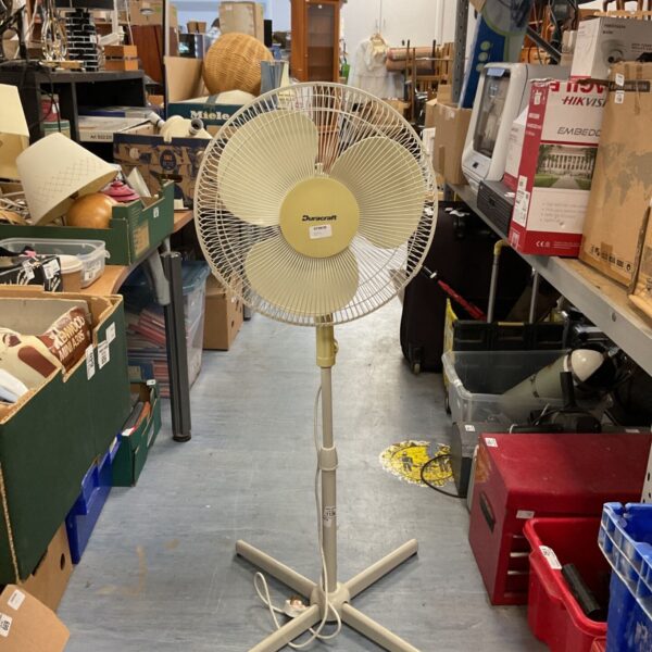 Cream Dunecraft pedestal fan in a cluttered room.