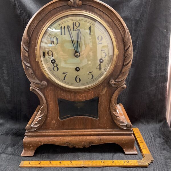 Front view of antique Edwardian balloon bracket clock with carved oak.