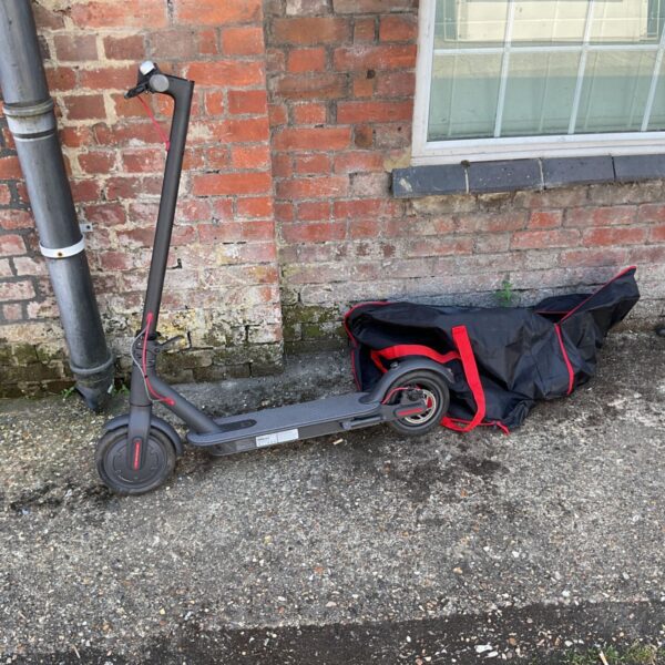 Black and red electric scooter with charger and spare tires.