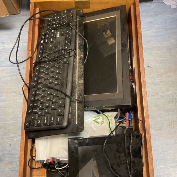 Tray of mixed electronics accessories including a computer keyboard and cables.