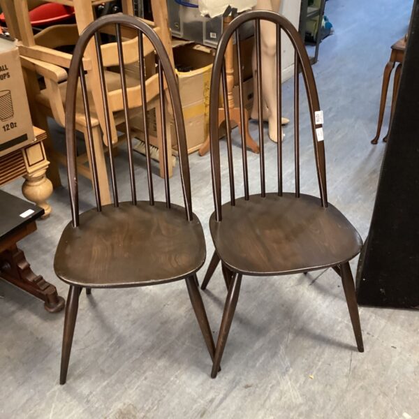Pair of dark wood Ercol stickback dining chairs in a vintage setting.