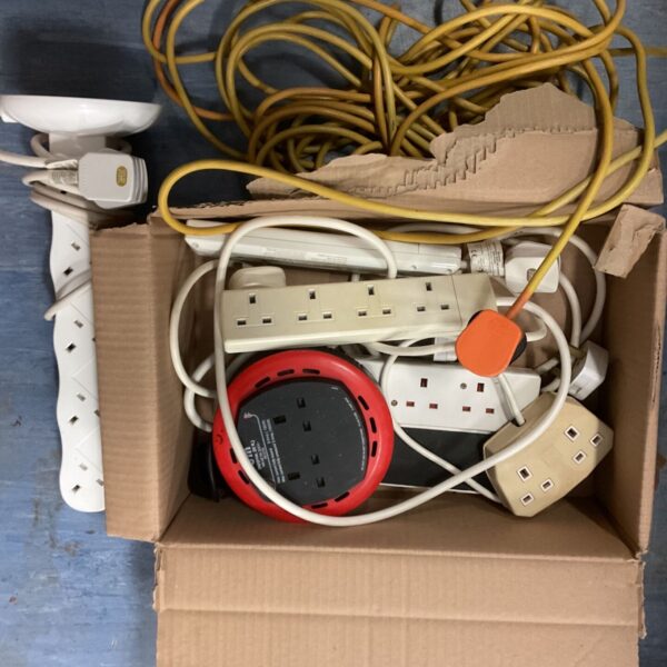 Box of assorted extension cables and power leads.