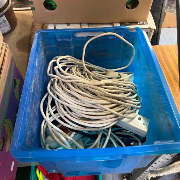 Assorted extension cords in a blue storage container.