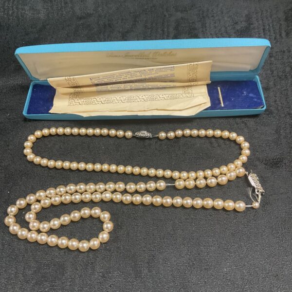 Lot of two vintage faux pearl necklaces on display.