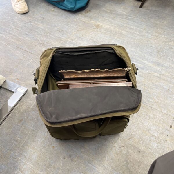 Green fishing bag filled with wooden picture frames.