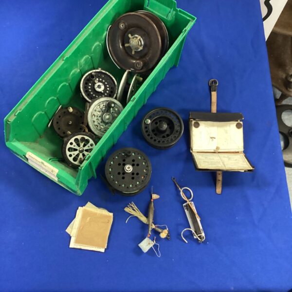 Vintage fly fishing reels and flies in a green container.