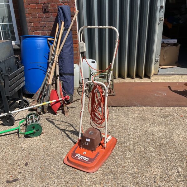 Vintage Flymo electric hover mower in orange, showing signs of wear.