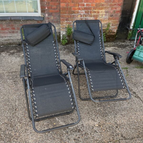 Pair of black folding garden recliner chairs in a garden setting.