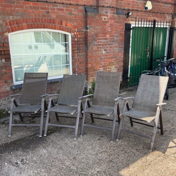 Set of four grey folding garden chairs in a garden setting.