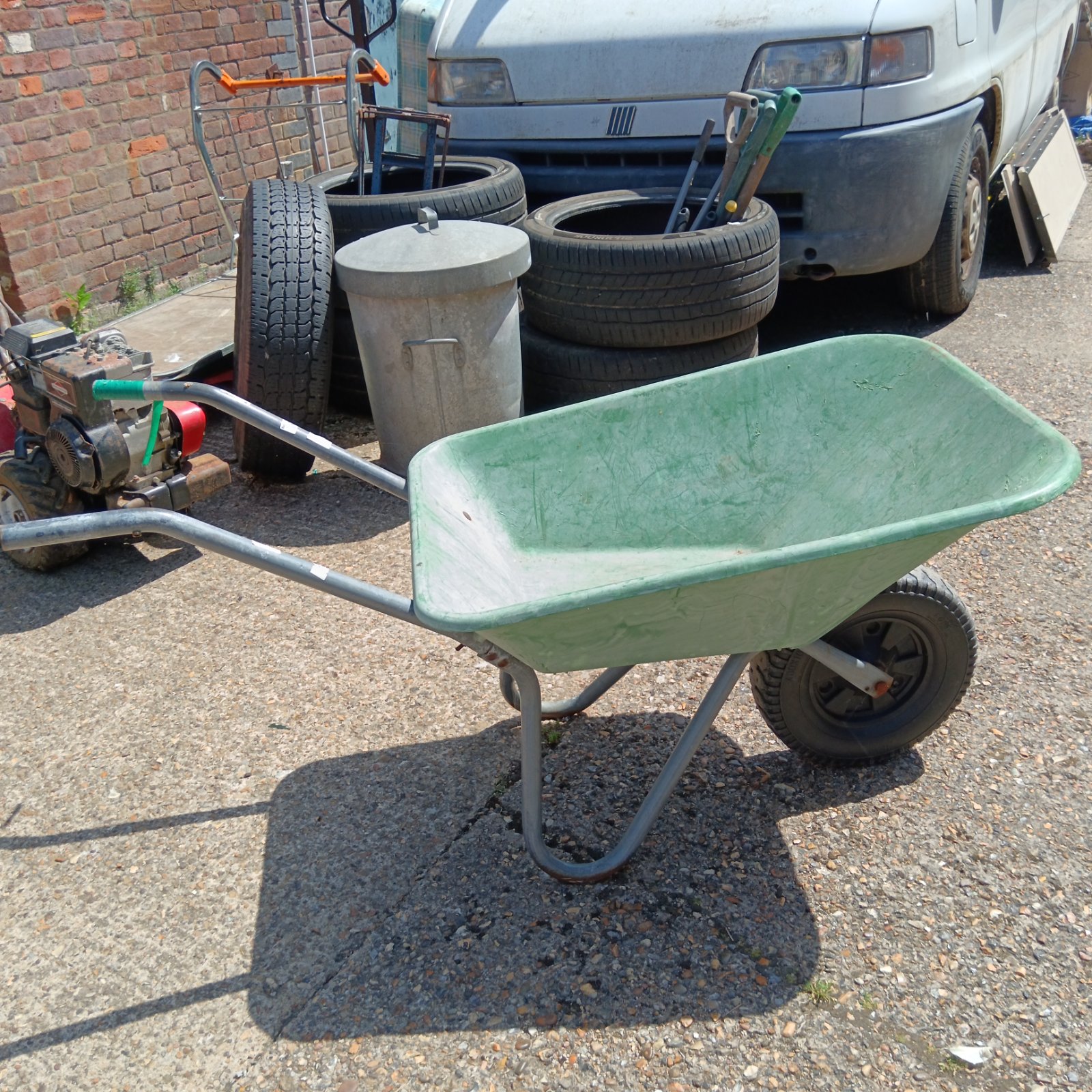 Green Fort plastic wheelbarrow in a garden setting.
