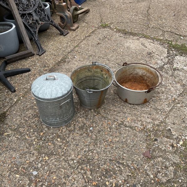 Vintage galvanised buckets and a metal jam pot in a garden setting.