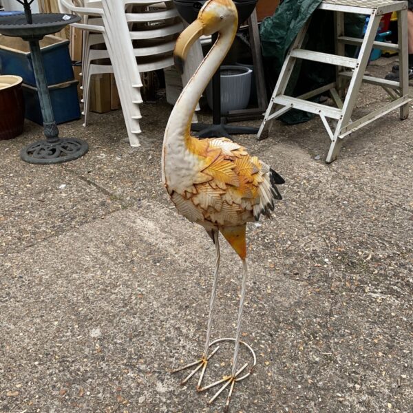 Vintage metal garden flamingo ornament in a garden setting.