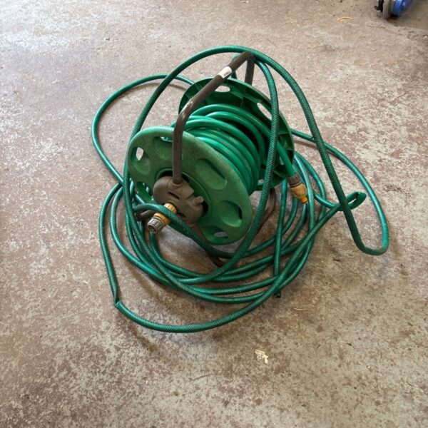 Green garden hose reel with hose wound around it.