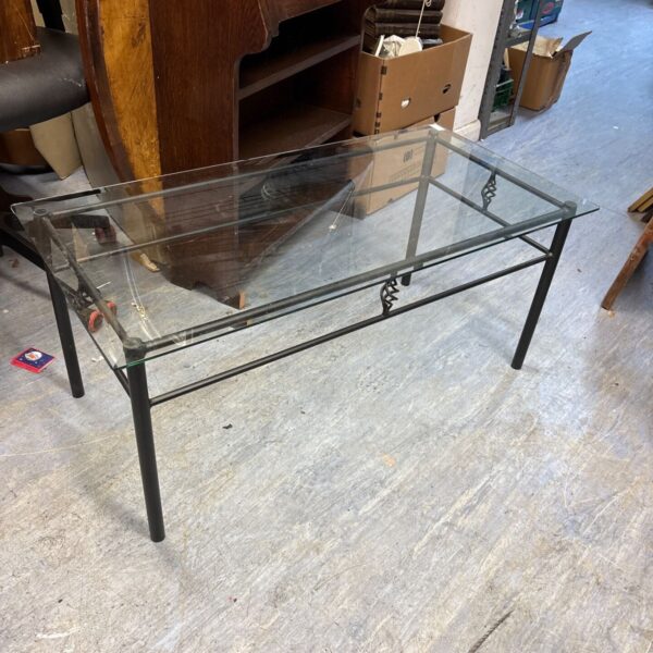 Modern glass coffee table with metal frame in a living room setting.
