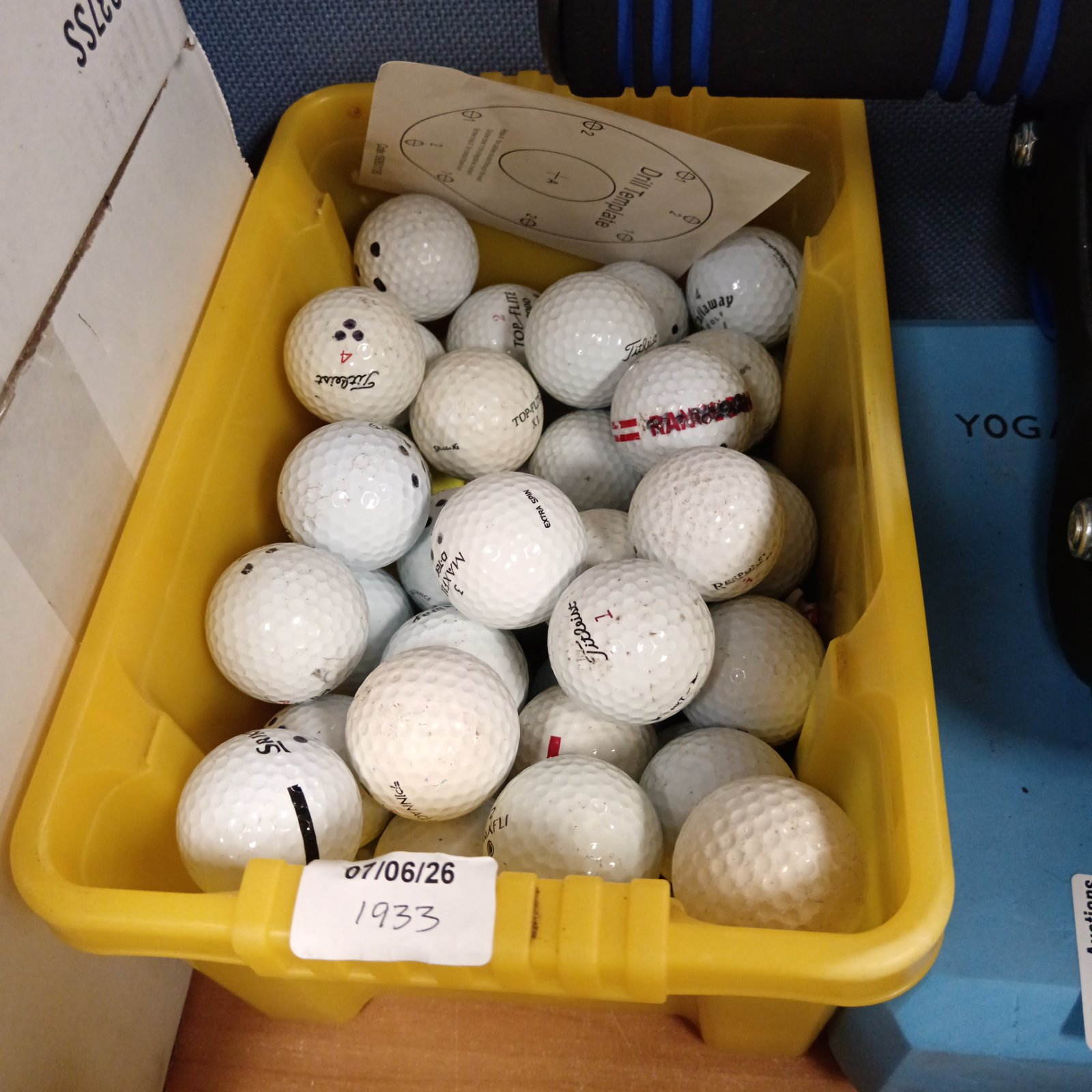 Used golf balls including Titleist in a yellow container.