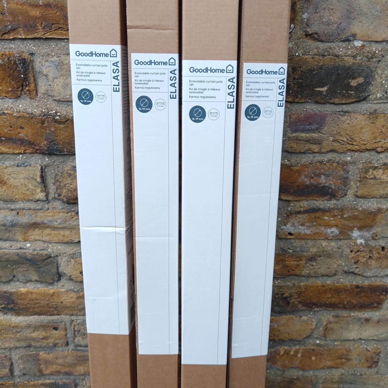 Stack of four boxed GoodHome extendable curtain poles.