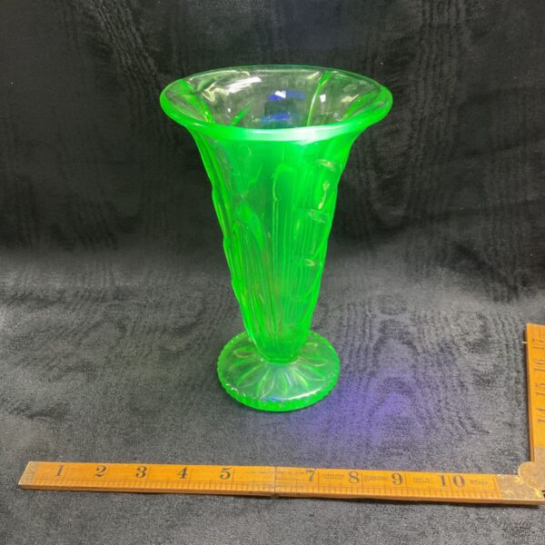 Vintage green uranium glass trumpet vase on ruler.
