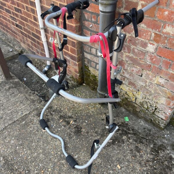 Halfords 3 bike rear rack shown against a brick wall.