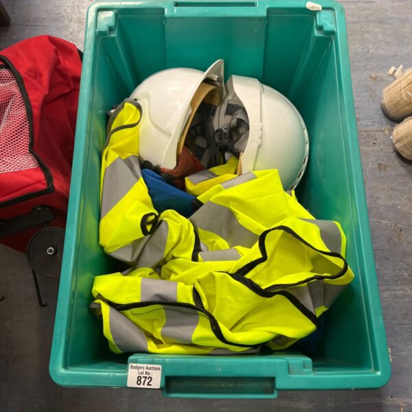 Box of hi vis vests and white hard hats for work safety.