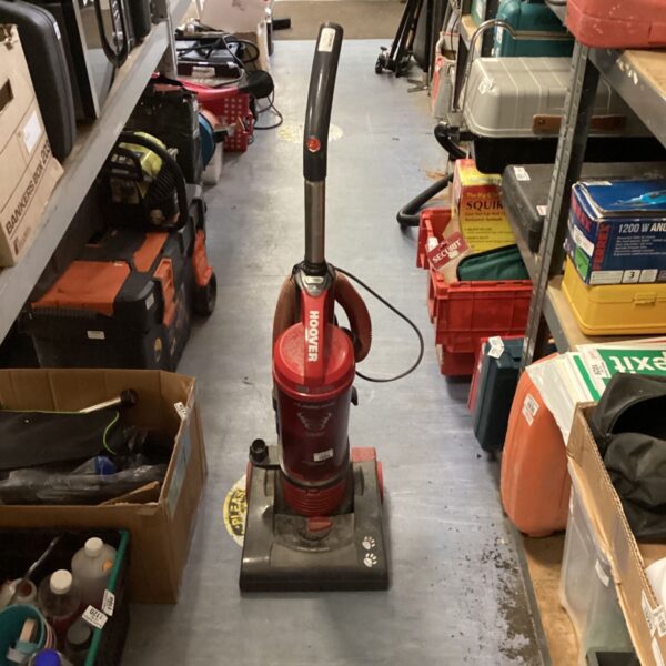 Red Hoover Hurricane cyclonic vacuum cleaner in a cluttered space.