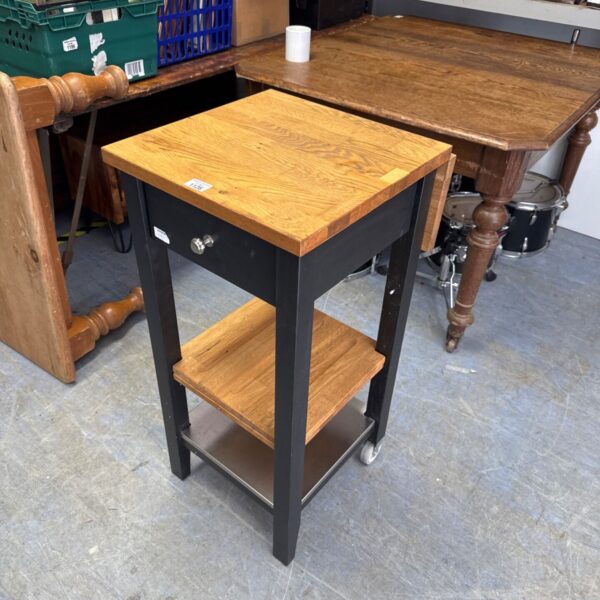 Ikea butcher block table with black base and rolling casters.