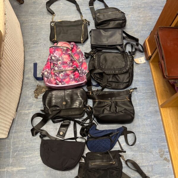 Job lot of mixed handbags and purses on display.