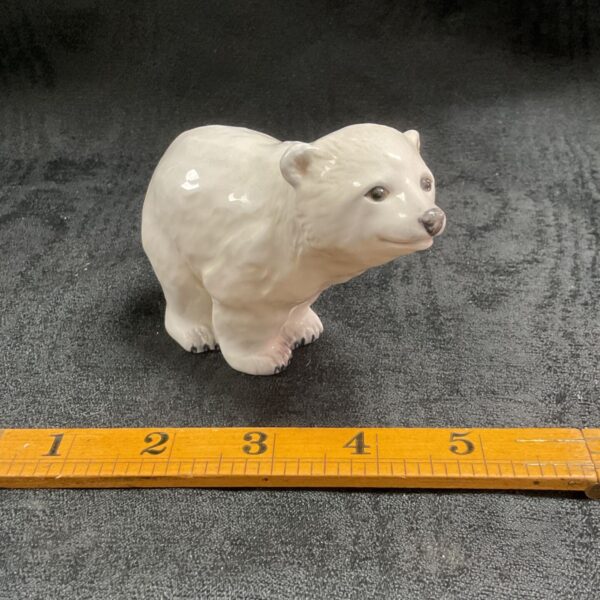 White John Beswick polar bear figurine on ruler.