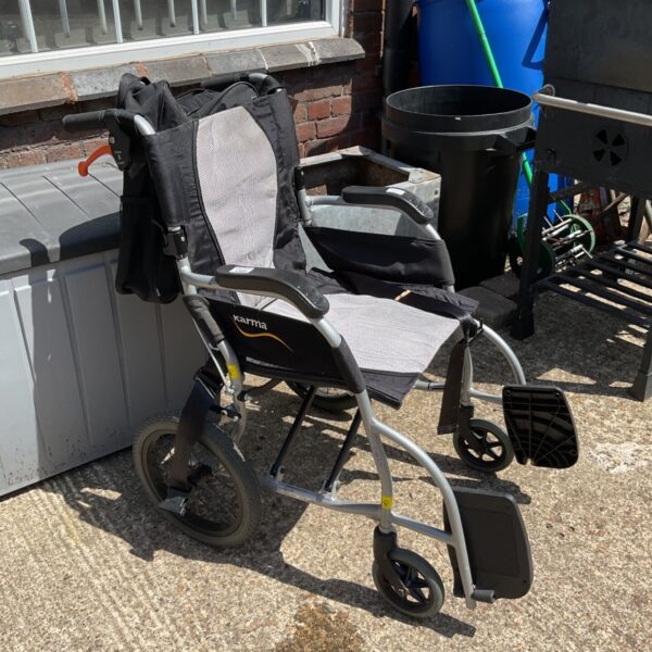 Grey Karma folding wheelchair with black accents, side view.