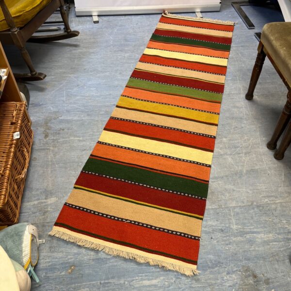 Vibrant Kilim runner rug with orange, green, red, and yellow stripes.
