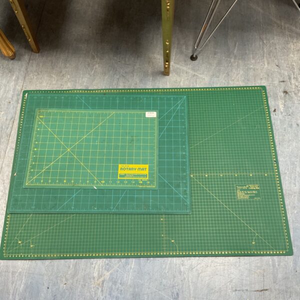 Large green cutting mat with grid lines for crafting and quilting.