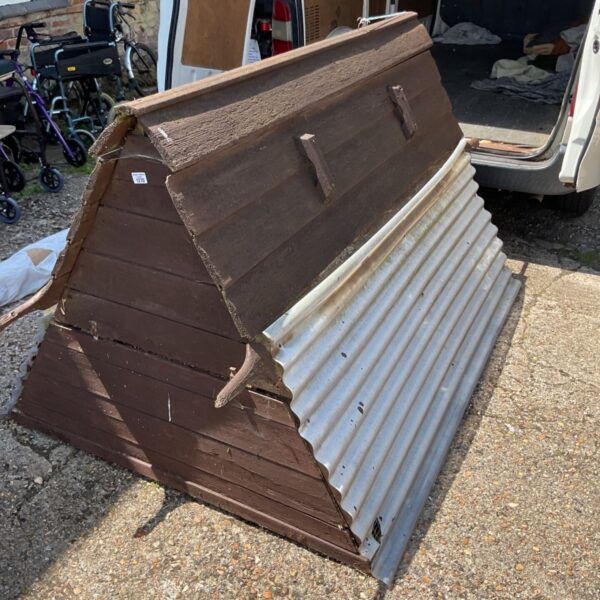 Large wooden chicken coop needing restoration in a garden setting.