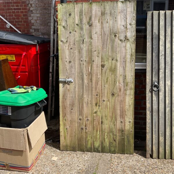 Large wooden gates with metal hardware in a garden setting.