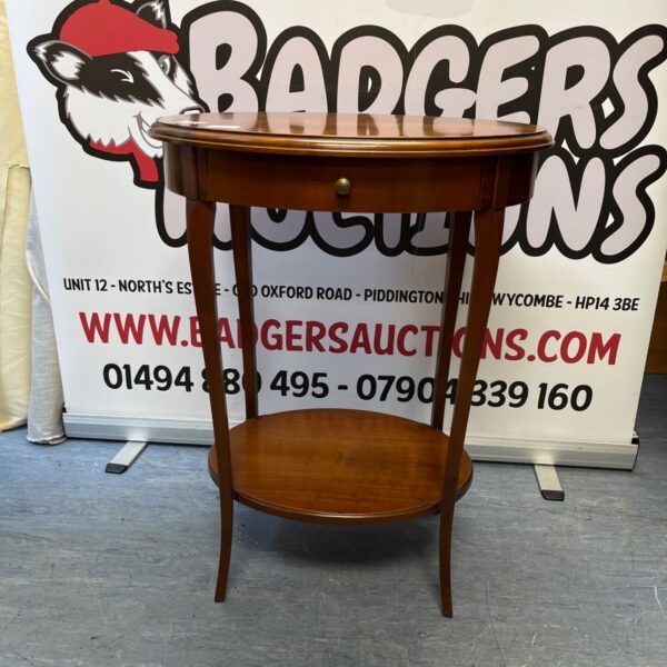 Vintage mahogany side table with oval top and brass knob.