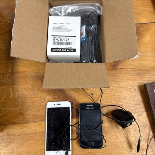 Mazda CarPlay system with damaged iPhone and Samsung phone.