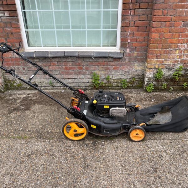 Yellow and black McCulloch petrol lawn mower in a garden setting.