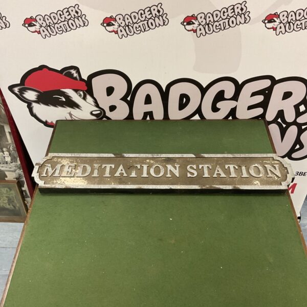 Vintage metal meditation station sign with weathered paint.