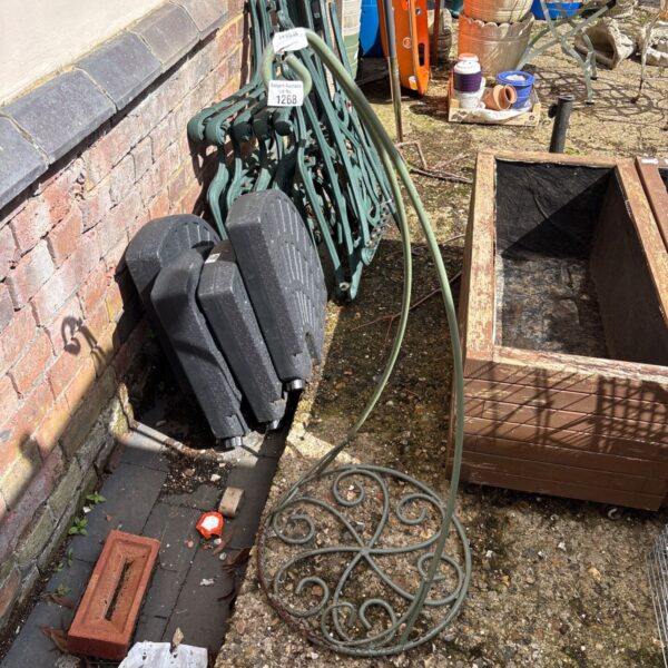 Vintage metal hanging basket cradle in a garden setting.