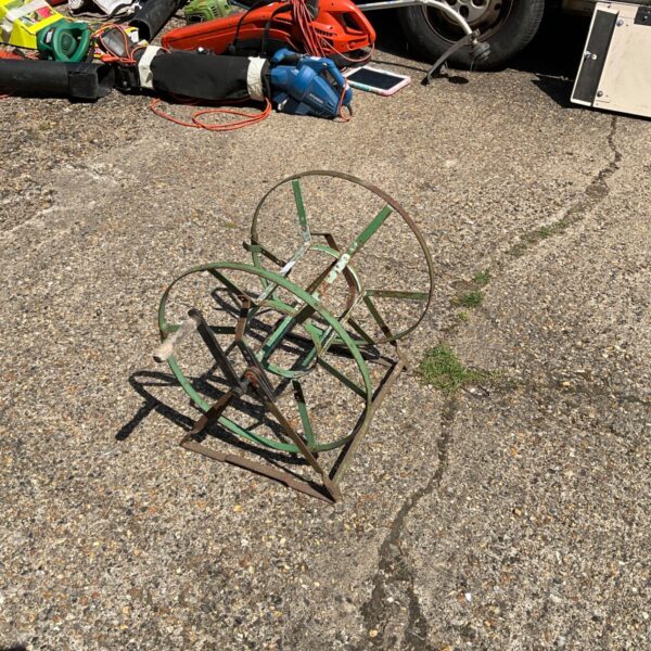 Vintage metal hose reel for garden hose storage in a yard.